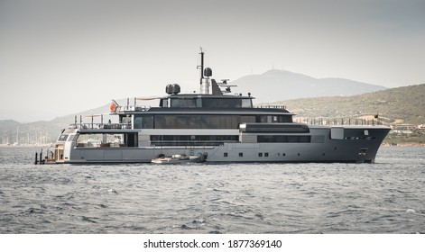 Beautiful Ultra Modern Super Yacht Anchored In The Cala Di Volpe, Sardinia With Tender And Crew On Deck