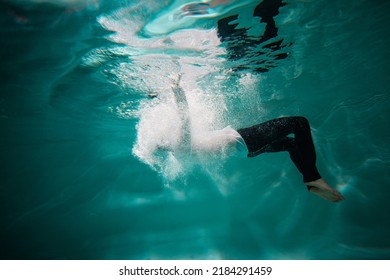 Beautiful underwater shooting, guy in white shirt and pants has fallen under the water and drowning. go to bottom, concept. young man paddles with his hands under water, waves and splashes around - Shutterstock ID 2184291459