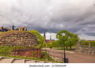 Beautiful Uppsala city landscape view. Tourist group on hill under heavy clouds sky. Uppsala. Sweden. Europe. 05,14,2022.