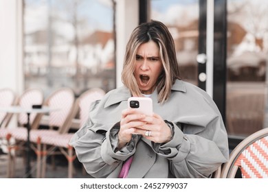 Beautiful upset woman sitting alone near big window in coffee shop, relaxing in restaurant during free time. Sad angry female having talking conversation with mobile phone, yelling. Screaming woman. - Powered by Shutterstock