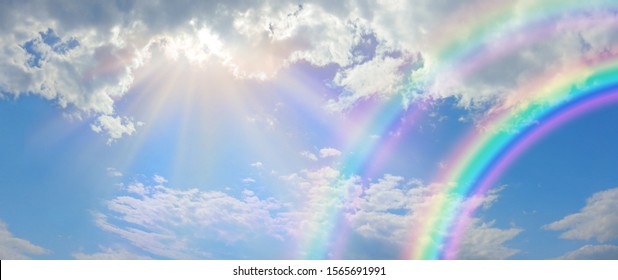 Beautiful vibrant double rainbow Cloudscape Background - awesome blue sky with pretty clouds, bright sun shining down and a large double rainbow arcing across the right corner with copy space

