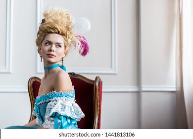 Beautiful Victorian Woman In Wig With Feathers Sitting On Antique Chair 