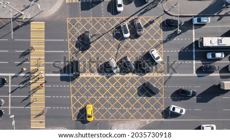 Beautiful view from above to a busy crossroad in a big city. Camera moving upwards showing cars and trucks turning at the intersection while others waiting at the traffic lights.