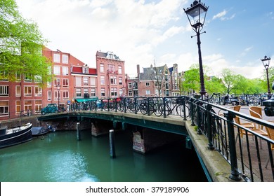 Beautiful View Of Amsterdam Canal With Lantern And Bridge During Summer Time With Cloudy Sky