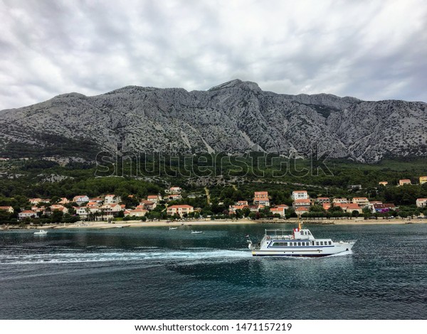 A beautiful view of a boat passing by Orebic\
on the Peljesac Peninsula, in beautiful Croatia.  The mountains are\
in the background.