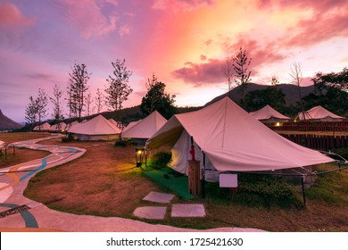Beautiful view of canvas glamping bell tents in a green field with walkway at mountains in beautiful sky with cloud before sunrise.