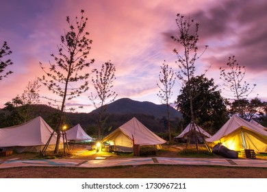 Beautiful view of canvas glamping bell tents in a green field with walkway at mountains in beautiful sky with cloud before sunrise.