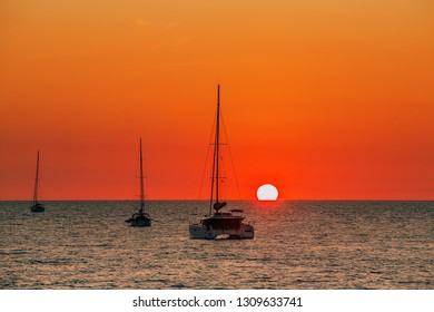 Beautiful View Of Catamaran Sailboats, Yacht Cruises In Silhouette Against Tropical Sunset With Sun Reflection On The Sea At Layan Beach, Phuket, Thailand. Boat Trip Escape At Dream Destination.