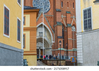 Beautiful view of cathedral church with people standing near entrance between old buildings. Europe. Sweden. Uppsala. 05.14.2022.