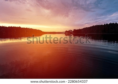 Beautiful view of colorful summer sunset or sunrise by forest lake in Sweden, Sunset or sunrise with bright colors in th sky and reflections in the water