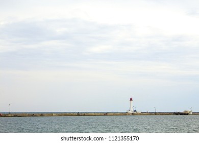 Beautiful view. The current lighthouse. Vorontsov lighthouse in Odessa against the background of the Black Sea, closeup. White tower with a red cabin at the top on a background of blue seascape