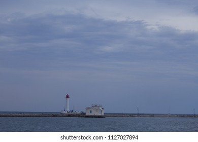 Beautiful view. The current lighthouse. Vorontsov lighthouse in Odessa against the background of the Black Sea, closeup. White tower with a red cabin at the top on a background of blue seascape
