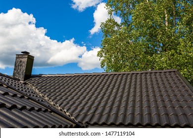 Beautiful View Of Dark Gray Tiled Roof On Tops Of Green Trees And Blue Sky Background. Beautiful Backgrounds.