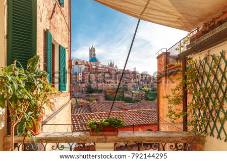 Beautiful view of Dome and campanile of Siena Cathedra, and Old Town of medieval city of Siena in the sunny day through autumn leaves, Tuscany, Italy