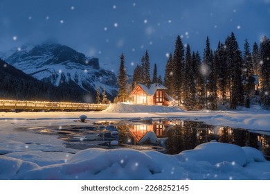 Beautiful view of Emerald Lake with wooden lodge glowing and snowfall in pine forest on winter at Yoho national park, Alberta, Canada