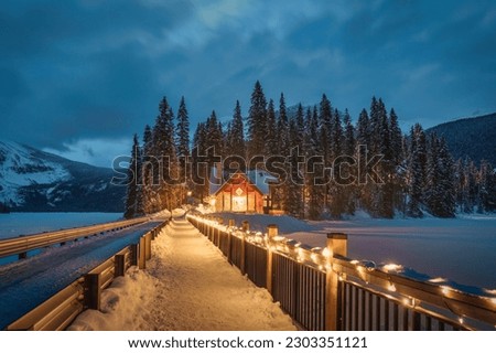 Beautiful view of Emerald Lake with wooden lodge glowing in snowy pine forest on winter at Yoho national park, Alberta, Canada