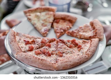 Beautiful view of the food. A beautiful background, a view of a triangular hunk, a part, a slice of delicious meat and sausage pizza with tomatoes, cakes of flour and dough on a white ceramic dish. - Shutterstock ID 1362310316