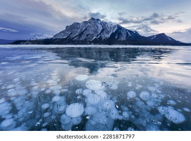 beautiful view of Frozen Abraham Lake with rocky mountains and natural bubbles frost in the morning on winter at Banff national park, Alberta, Canada - Powered by Shutterstock