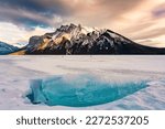 Beautiful view of Frozen Lake Minnewanka with rocky mountains and cracked ice from the lake in winter at Banff national park, Alberta, Canada