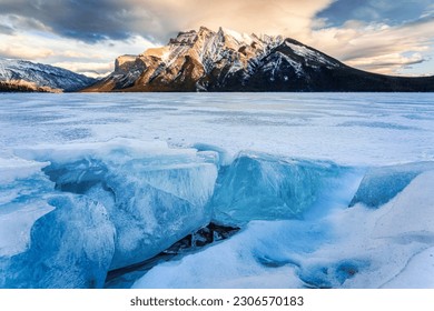 Beautiful view of Frozen Lake Minnewanka with rocky mountains and cracked ice in winter at Banff national park, Alberta, Canada - Powered by Shutterstock