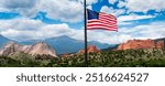 Beautiful view of Garden of the Gods in Colorado Springs with a new colorful American Flag flying high above the stone formations and Pikes Peak. 