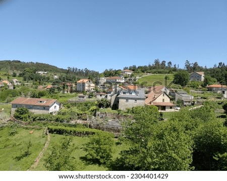 Beautiful view of the gently rolling countryside of Galicia. In spring, when life awakens, all the trees are green and the sky is bright blue. Typical Galician houses stand sporadically in the landsca