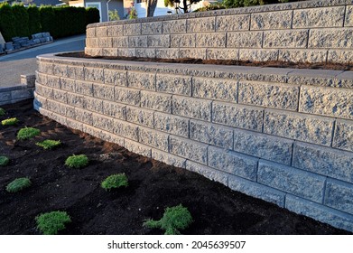 A beautiful view of a gray colored 2 tier retaining wall built with concrete blocks in early morning sunlight. - Shutterstock ID 2045639507