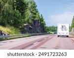 Beautiful view of highway passing between rocky mountains on summer day with camper van and other vehicles on move. Sweden.