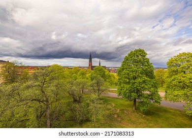 Beautiful view from hill to landscape of city of Uppsala with cathedral against backdrop of thunderclouds on summer day. Sweden.