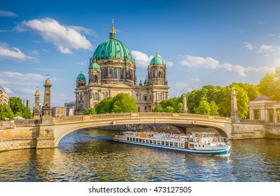 Beautiful view of historic Berlin Cathedral (Berliner Dom) at famous Museum Island with ship passing Friedrichsbrucke bridge on Spree river in golden evening light at sunset in summer, Berlin, Germany