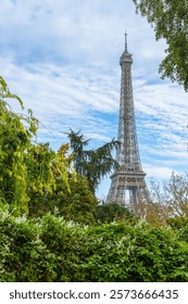Beautiful view of the iconic Eiffel Tower surrounded by trees against blue sky. Paris, France 