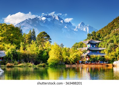 Beautiful view of the Jade Dragon Snow Mountain and the Moon Embracing Pavilion on the Black Dragon Pool in the Jade Spring Park, Lijiang, Yunnan province, China.