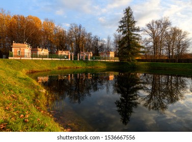 Beautiful view of Kuskovo park in Moscow at sunny autumn evening with lush green grass, yellow leaves and pond with reflection of blue cloudy sky, pine tree and bird houses. Kuskovo, Moscow - Powered by Shutterstock