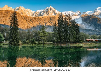 Beautiful view of Lac des Gaillands with train passing and Mont Blanc massif reflection in the sunset at Chamonix, Haute Savoie, France - Powered by Shutterstock