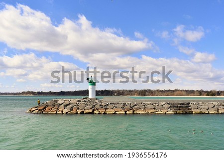 Beautiful view of Lake Ontario with a person by the lighthouse along the breakwater pier in Pickering, Ontario, Canada