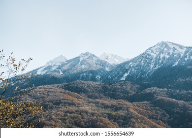 Beautiful View Of Landscape Through Autumn Forest To The High Mountains In The Snow. Transition From Autumn To Winter.