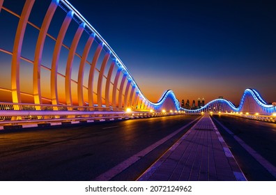 Beautiful view of Meydan Bridge in Dubai. Modern artistic bridge in Dubai. Night architectural shot of a bridge with curvy blue lights.
