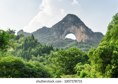 Beautiful view of Moon Hill and green woods at Yangshuo County of Guilin, China. Wonderful karst mountain with natural arch on sky background. Moon Hill is a popular tourist destination of Asia.