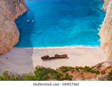 Beautiful view on Shipwreck beach in amazing bay, boats and ships with swimming people in Ionian Sea blue water, Blue Caves shipwreck beach. Greece Island Zakynthos holidays. Navagio beach view point