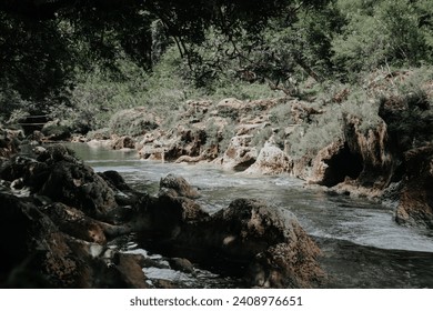 Beautiful view of the river with rocky banks, clear water flowing in the middle of a calm forest - Powered by Shutterstock