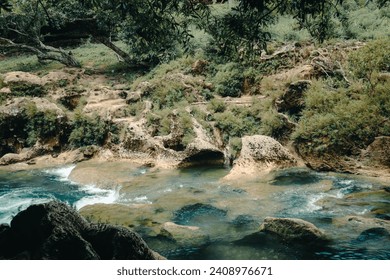 Beautiful view of the river with rocky banks, clear water flowing in the middle of a calm forest - Powered by Shutterstock