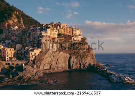 Beautiful view of rocky hills and colorful historic buildings of Manarola, tourist attraction and famous place in Liguria, Italy. Hillside over the sea at sunset. Foto d'archivio © 