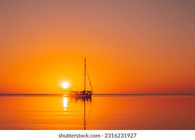 A beautiful view of a sailing boat silhouette in the ocean at sunset in Southern Belize.