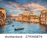 Beautiful view of traditional Gondola on famous Canal Grande with Basilica di Santa Maria della Salute in golden evening light at sunset in Venice, Italy