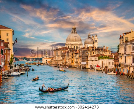 Beautiful view of traditional Gondola on famous Canal Grande with Basilica di Santa Maria della Salute in golden evening light at sunset in Venice, Italy