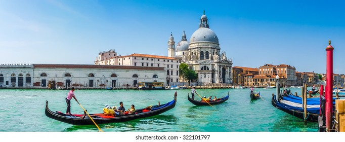 Beautiful view of traditional Gondolas on Canal Grande with historic Basilica di Santa Maria della Salute in the background on a sunny day in Venice, Italy
