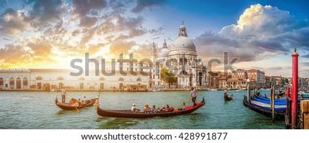 Beautiful view of traditional Gondolas on famous Canal Grande with historic Basilica di Santa Maria della Salute in the background in romantic golden evening light at sunset in Venice, Italy