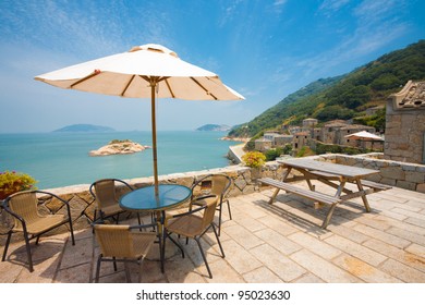 A beautiful view of Turtle island seen at rest area beige brick patio viewpoint with tables, chairs, picnic area in the stone Qinbi village on Beigan, Matsu Islands, Taiwan. Horizontal copy space