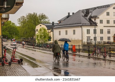 Beautiful view of Uppsala city center with people cycling along the river under umbrellas. Sweden. Uppsala. 05.14.2022.