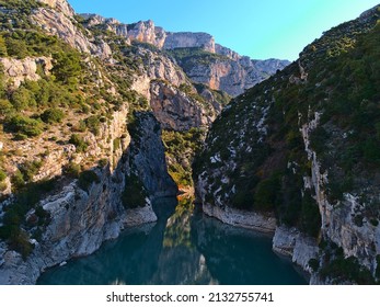 Beautiful view of the western narrow entrance of majestic canyon Verdon Gorge (Gorges du Verdon) in Provence region, France with rugged limestone rocks reflected in the calm water in autumn season. - Shutterstock ID 2132755741